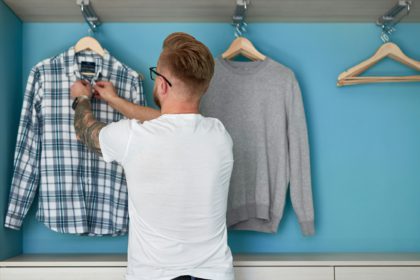 Man organizing garments in wardrobe